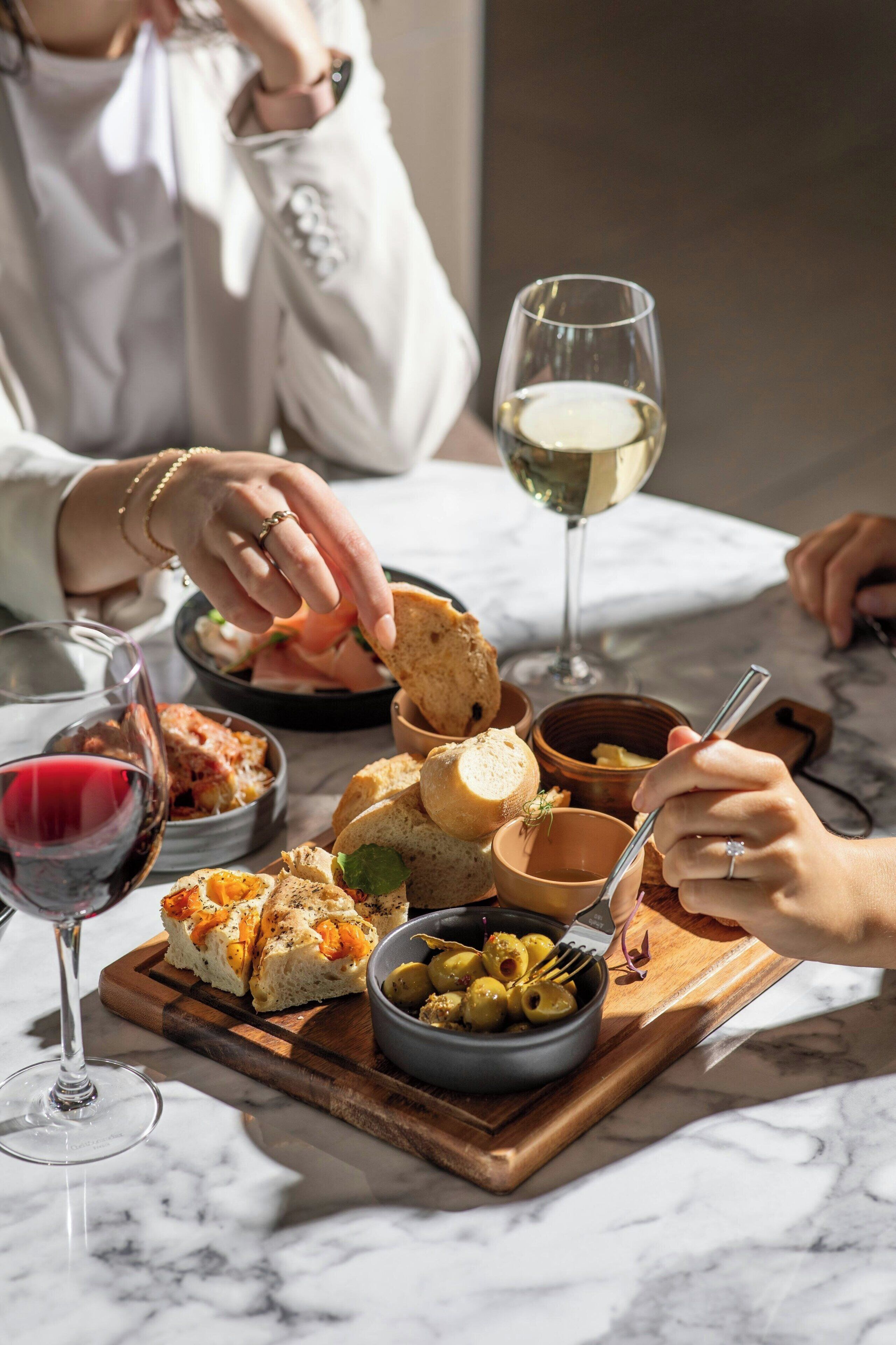 A dining table with various food items and glasses of wine.