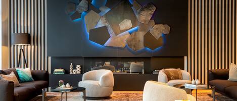 A modern living room with a fireplace, sofas, and a unique wall art piece.