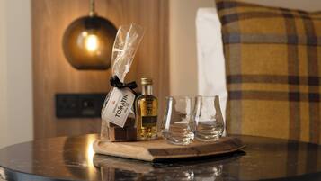 A round table with a bottle of Tomatin, a glass, and two empty glasses on a wooden board.