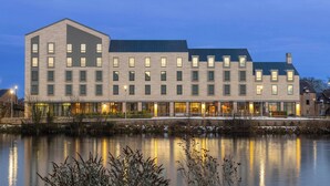 A modern hotel with a symmetrical facade, multiple windows, and a reflection in the water. - AC Hotel by Marriott Inverness (Inverness)