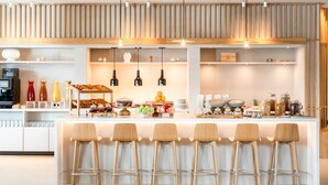 A modern kitchen with a central island, bar stools, and various food items. - AC Hotel by Marriott Inverness (Inverness)