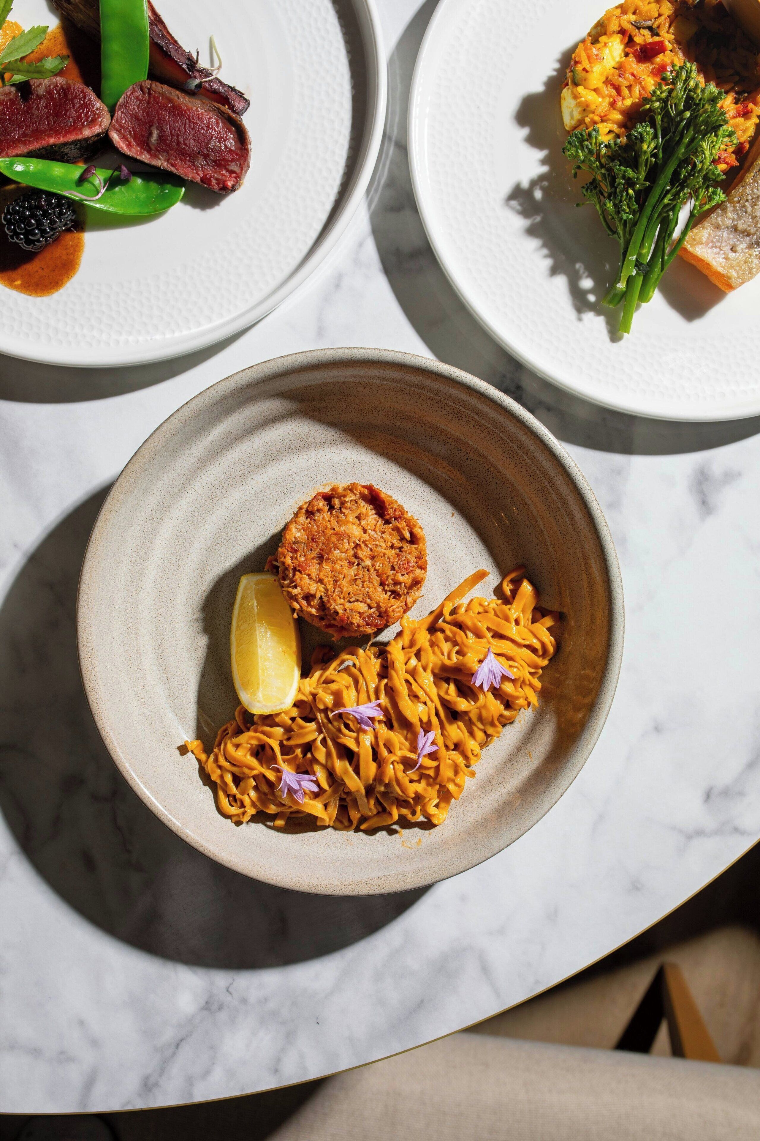 Tres platos de comida sobre una mesa de mármol.