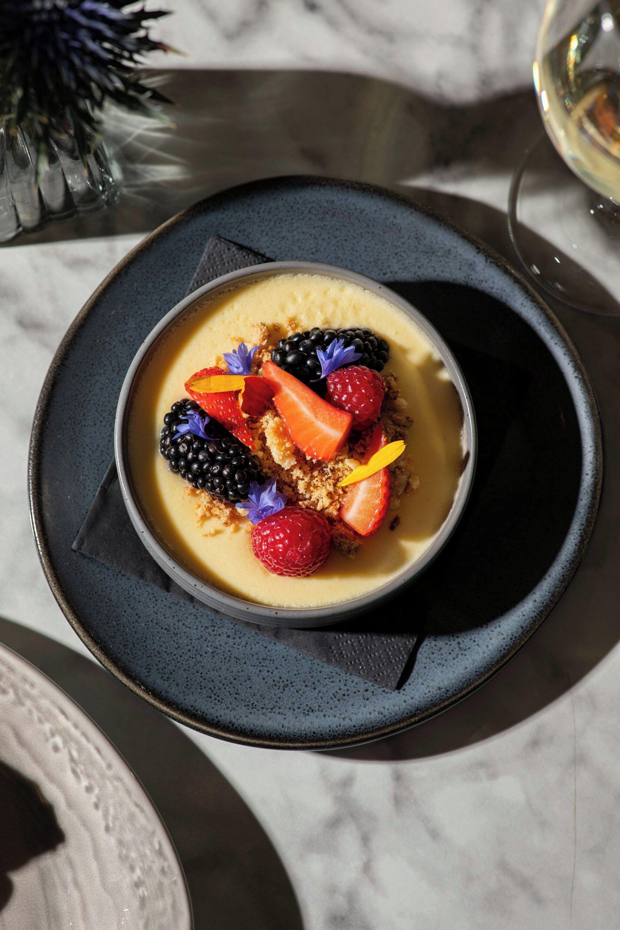 A dessert with berries and a flower on a plate.