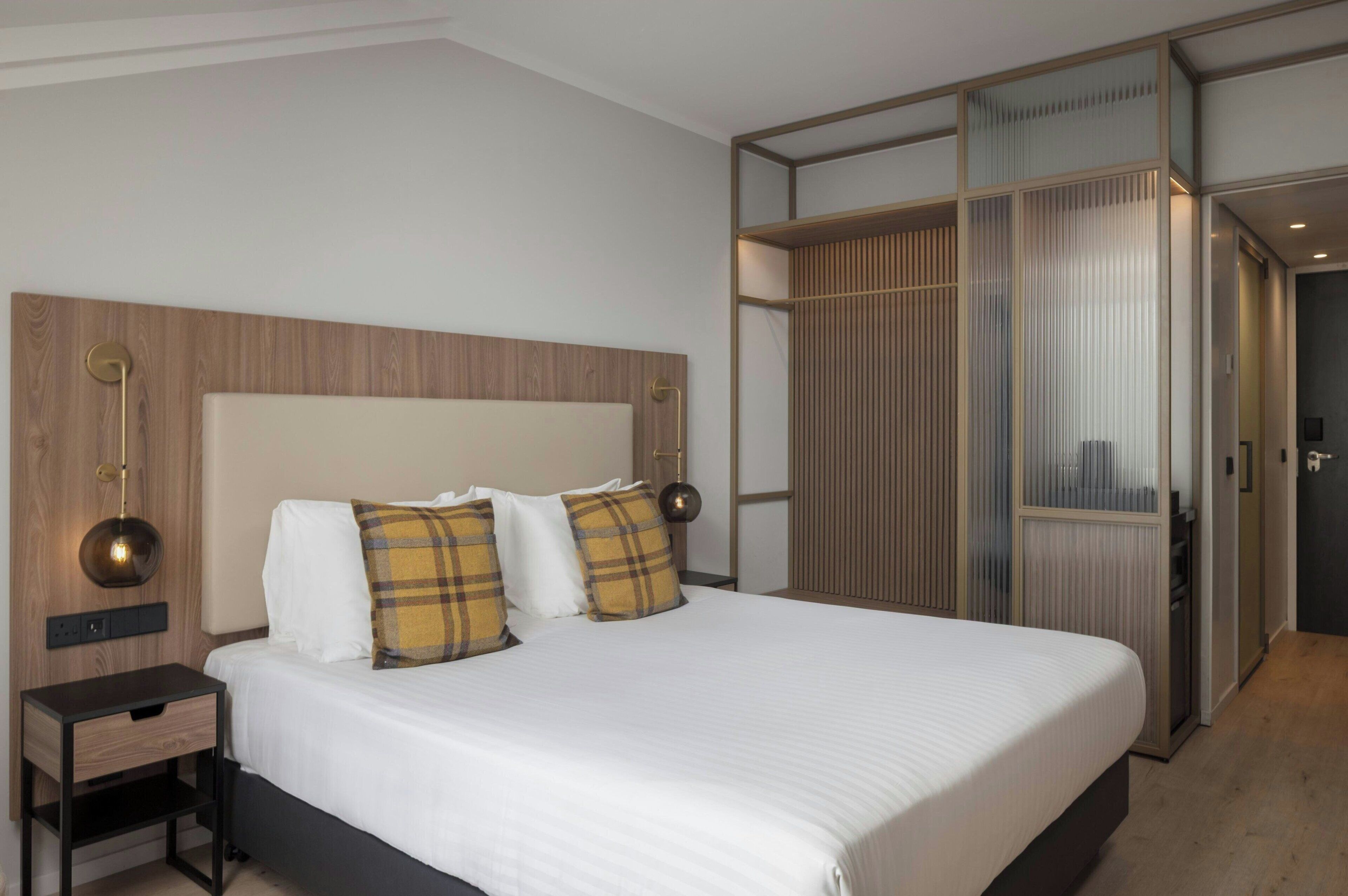 Een moderne hotelkamer met een groot bed, twee nachtkastjes en een inloopkast.