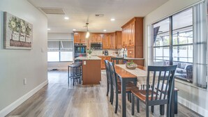Cocina amplia con armarios de madera, una isla central y un gran ventanal que proporciona luz natural.