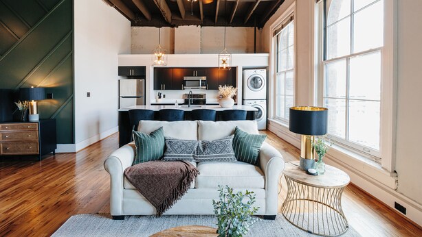 A modern living room with a sofa, a coffee table, and a dining area with a table and chairs. - Tailor Loft Studio| Living in the Heart of Knox (Knoxville)