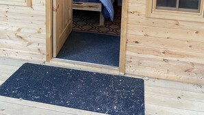 A wooden cabin with a bed, a welcome sign, and framed pictures on the wall. - Perfect 4-season cottage for year-round joy (Whitestone)