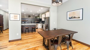 Una cocina moderna con una isla central, electrodomésticos de acero inoxidable y un comedor con una mesa de madera y sillas de metal.