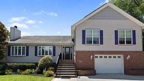 A two-story house with a front entrance, a garage, and a well-maintained lawn. - Pool Property in West Cape May - Sleeps 6 Guests (West Cape May)