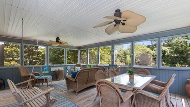 A covered outdoor area with wicker furniture, a glass table, and ceiling fans. - Pool Property in West Cape May - Sleeps 6 Guests (West Cape May)