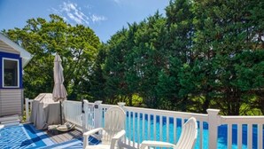 A deck with a blue patterned floor, white deck chairs, and a white fence surrounding a swimming pool. - Pool Property in West Cape May - Sleeps 6 Guests (West Cape May)