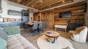 A modern kitchen with built-in appliances, a dining area with a wooden table and chairs, and a cozy living space with a sofa and armchairs. - Olvera 502 - New apartment on the slopes (VALMEINIER)