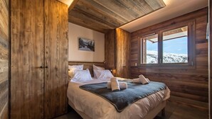 A wooden cabin bedroom with a bed, pillows, and a painting on the wall. - Olvera 502 - New apartment on the slopes (VALMEINIER)