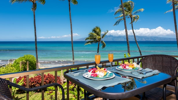 A table with a tropical breakfast setting overlooking a beach with palm trees and the ocean. - Perfect Romantic Getaway - Right on the Ocean! (Lahaina)