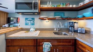 A modern kitchen with granite countertops, wooden cabinets, a stainless steel sink, a microwave, a coffee maker, and a toaster. - Perfect Romantic Getaway - Right on the Ocean! (Lahaina)