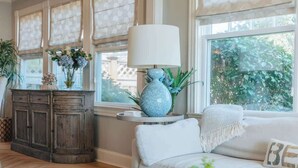 A living room with a sofa, a coffee table, a lamp, and a cabinet. - Beach Haven by STAY Newport (Middletown)