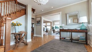 A spacious living area with a wooden staircase, a console table, a mirror, and a rug. - Beach Haven by STAY Newport (Middletown)