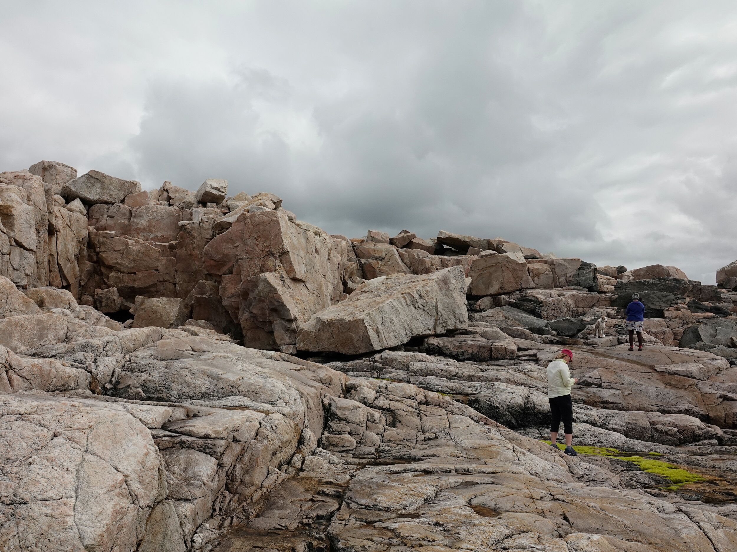A rocky terrain with large boulders and a cloudy sky.
