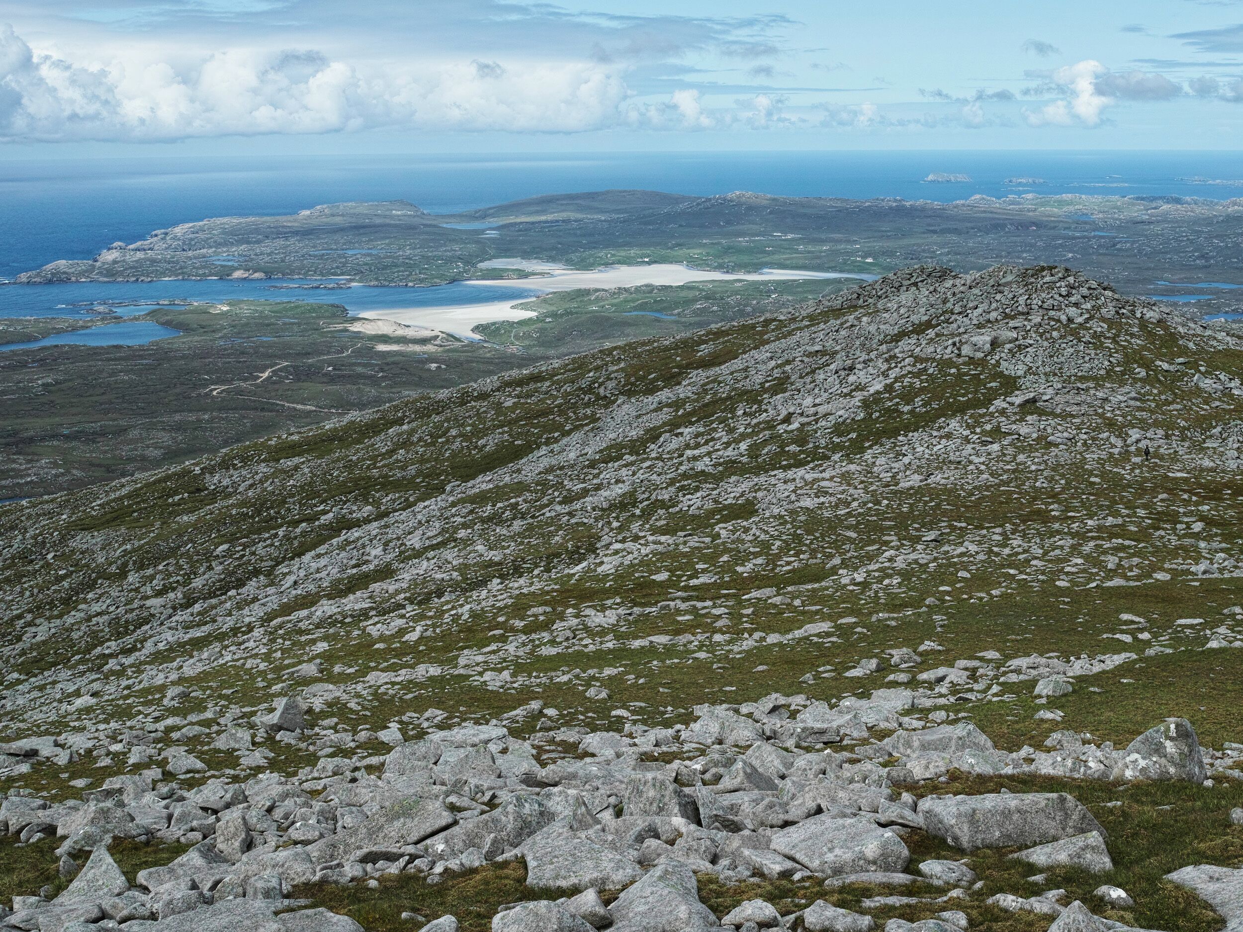 A rocky mountain landscape with a view of a coastal area in the distance.