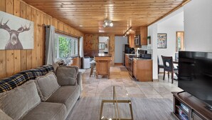 A wooden interior with a sofa, TV, kitchen, and dining area. - Charming Cabin on Dream Property (Pine)