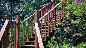 Un escalier en bois mène à un bâtiment entouré de verdure.