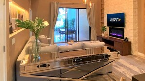 Ein modernes Wohnzimmer mit einer Couch, einem Glastisch, einem Kamin und einem an der Wand montierten Fernseher.