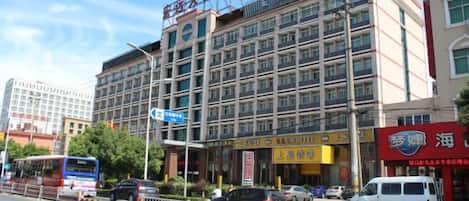 A multi-story hotel with a prominent sign, a street view with vehicles, and a clear sky.