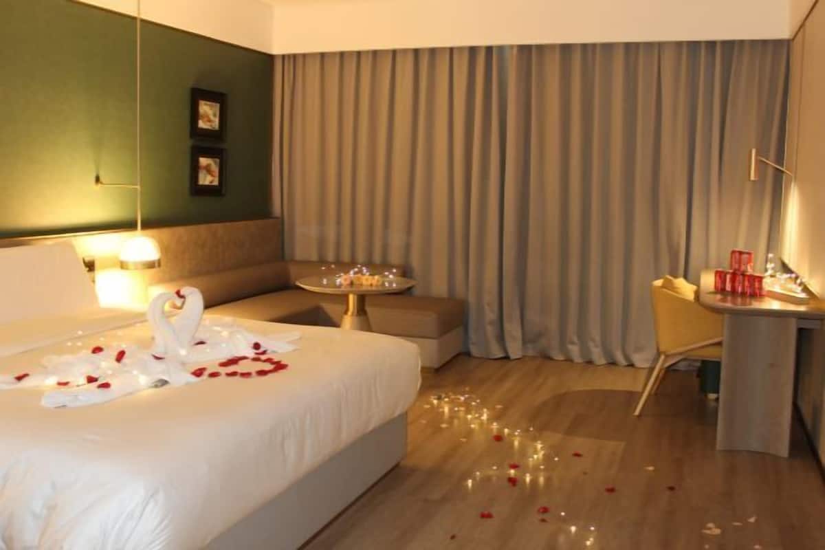 A hotel room with a bed, a small table, a sofa, and a desk.