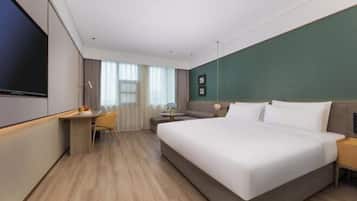 A hotel room with a large bed, a desk, a chair, a TV, and a window with curtains.