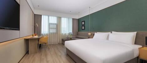 Ein Hotelzimmer mit einem großen Bett, einem Schreibtisch, einem Sessel, einem Fernseher und einem Fenster mit Vorhängen.