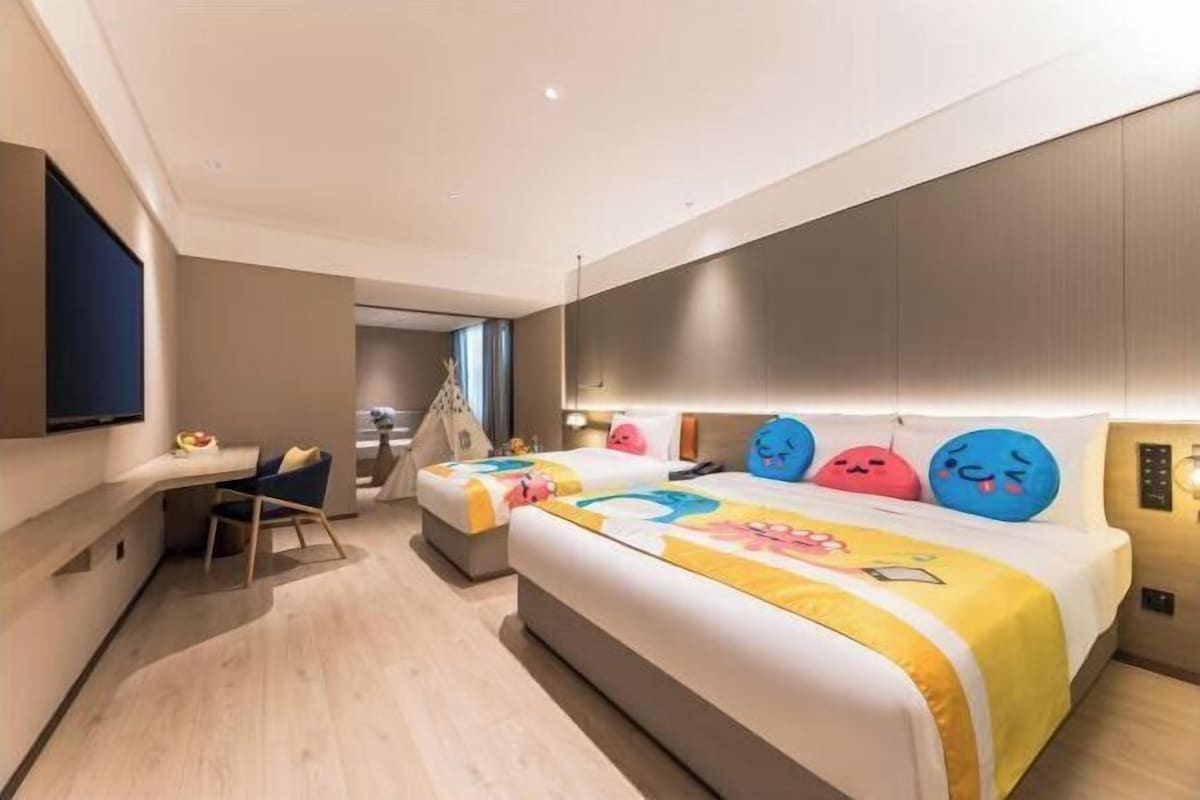 A modern hotel room with a large bed, a desk, and a TV.