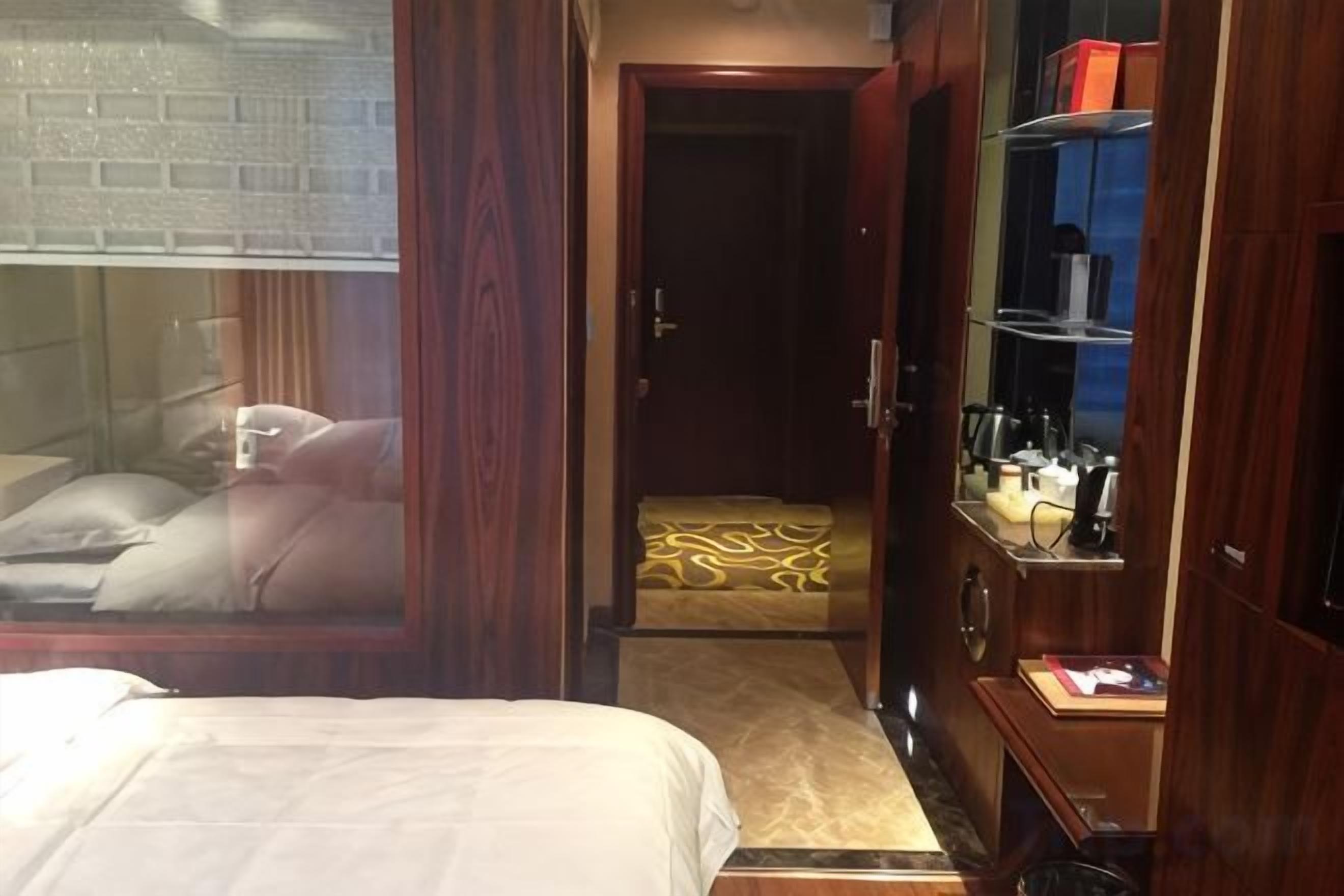 Een hotelkamer met een bed, een kledingkast, een spiegel en een zithoekje.