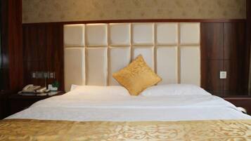 Habitación de hotel con una cama grande, un cabecero de madera, una mesita de noche con teléfono y una lámpara de pared.