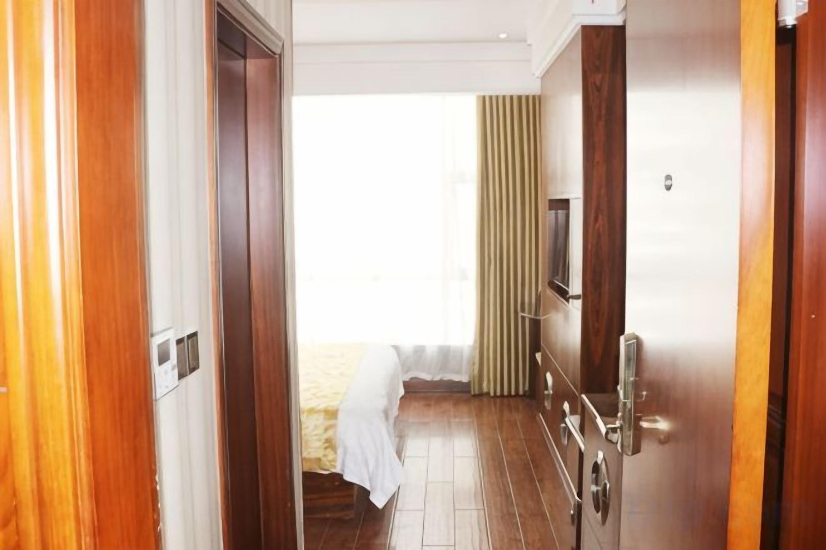 Un pasillo con una cama, zona de ducha y una puerta que da a una habitación.