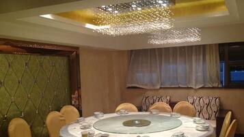 A round dining table with chairs, a chandelier, and a patterned wall.