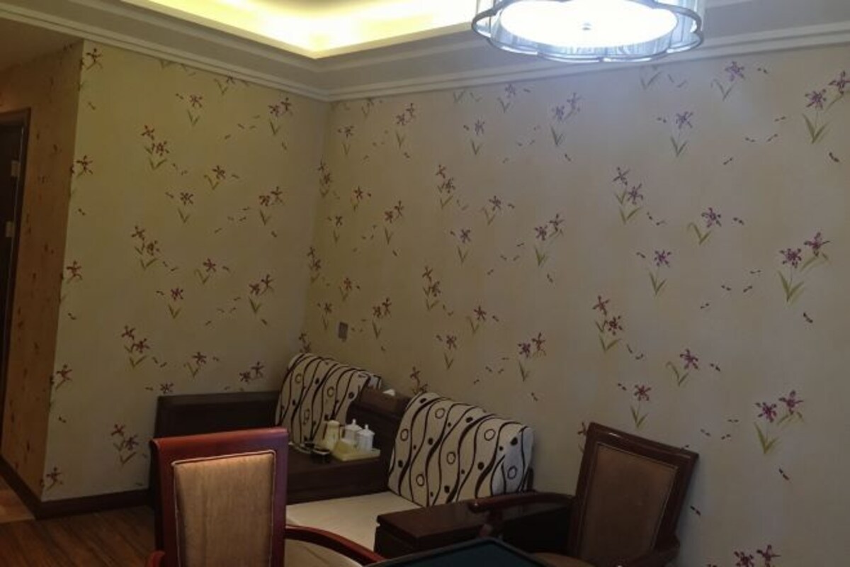 A room with floral wallpaper, a sofa, a chair, and a small table.