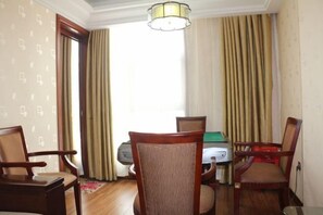 A room with a green pool table, four wooden chairs, a lamp, and a window with curtains. - Lihe Business Hotel (Huanggang)