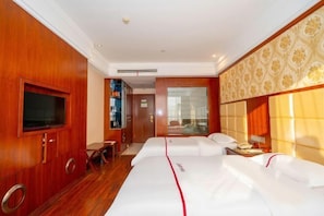 Une chambre d’hôtel avec deux lits, une télévision, un bureau et une fenêtre.