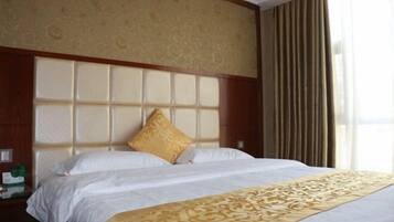 A hotel room with a large bed, a headboard with a patterned design, and a window with curtains.