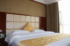 A hotel room with a large bed, a headboard with a patterned design, and a window with curtains. - Lihe Business Hotel (Huanggang)