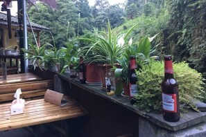 A wooden bench, potted plants, and bottles on a terrace with a view of greenery. - Wenfeng Villa (Ya'an)