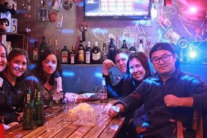 A bar with bottles and glasses on the counter, a television screen, and a neon sign. - Wenfeng Villa (Ya'an)
