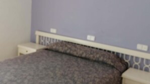 Ein Schlafzimmer mit einem Bett, weißen Nachttischen und einer violetten Wand.
