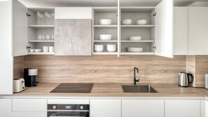 Een moderne keuken met witte kasten, een houten aanrechtblad, een inbouwgootsteen en een koffieapparaat.