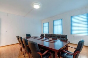 A conference room with a long table, multiple chairs, and a ceiling light. - National Hotel (Daozhen)