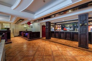 A hotel lobby with a reception desk, seating area, and a bar. - National Hotel (Daozhen)