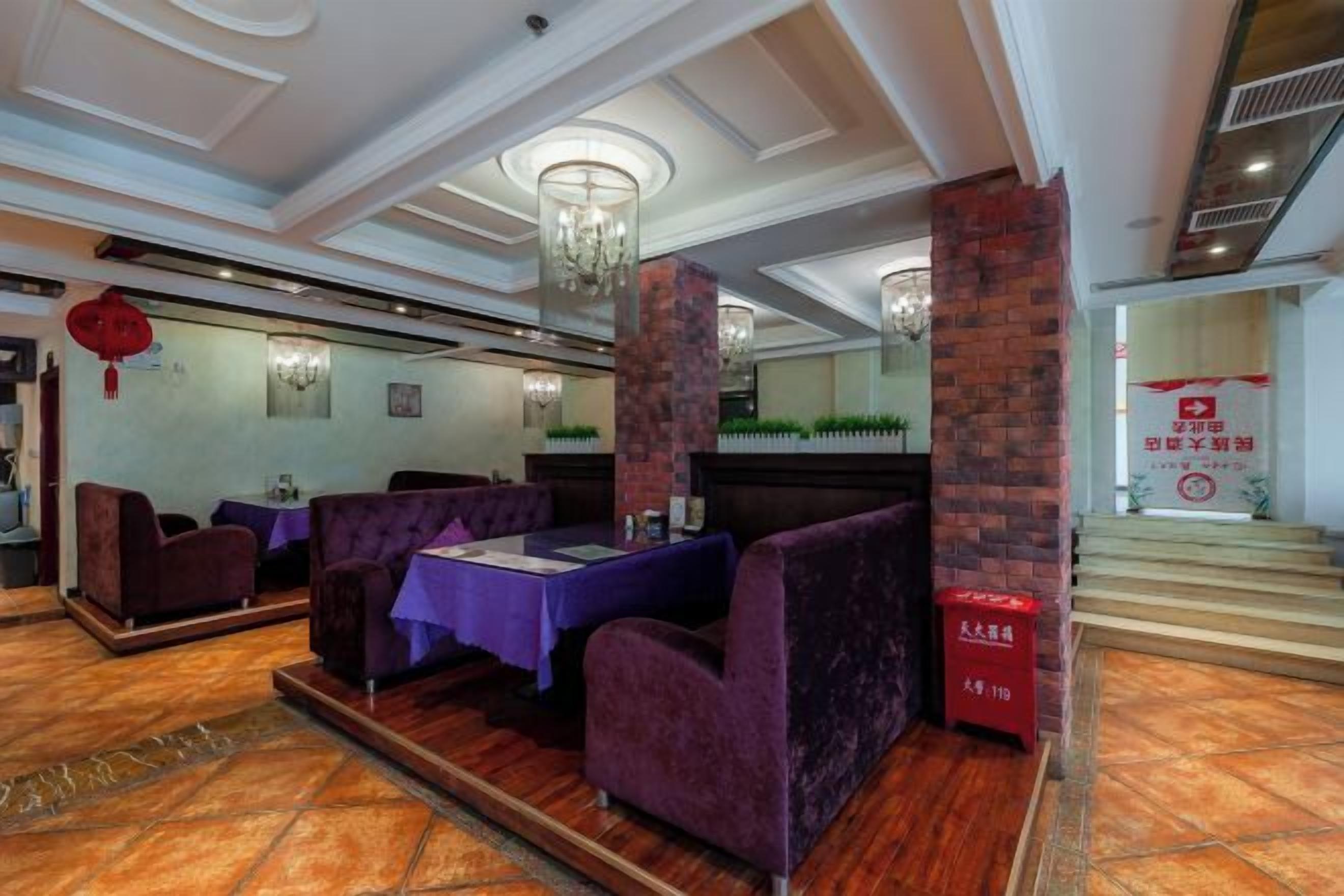 Un restaurante con asientos morados, una araña y una pared de ladrillo decorativa.