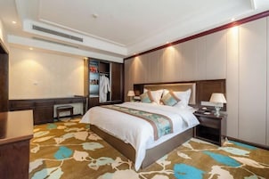 Habitación de hotel con una cama grande, un escritorio, un armario y una alfombra con diseño de hojas.