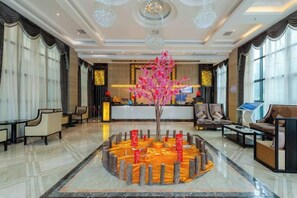 A lobby with a reception desk, seating area, and a decorative tree centerpiece. - National Hotel (Daozhen)