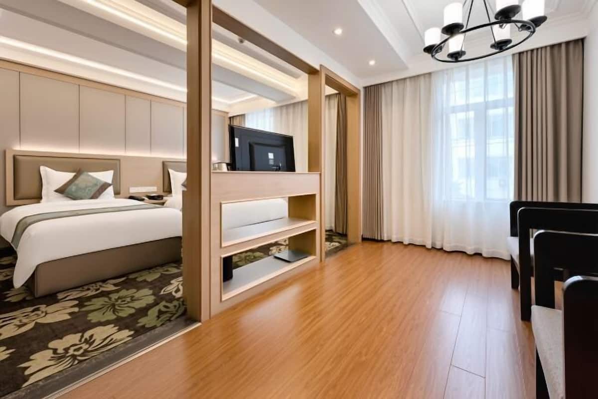 Habitació d'hotel amb un llit, una televisió sobre un suport, una taula i una cadira.